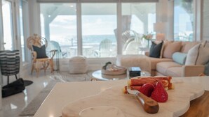 A modern living room with a marble table, a view of the sea, and a cozy seating area. - The Love Shack: Completely restored 1915 direct beachfront cottage! (BRADENTON BEACH)