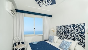 A bedroom with a bed, a chair, a window, and a decorative headboard. - Villa Blumarine - Private villa with pool and sea views (Positano)