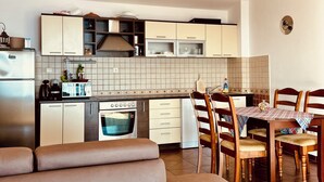 Una cocina moderna con horno empotrado, un comedor con mesa y sillas, y una zona de estar con sofá.