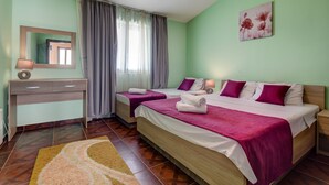 Una habitación de hotel con dos camas, un escritorio, un espejo y un cuadro en la pared.