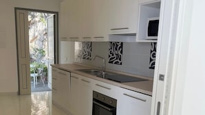 Una cocina moderna con armarios blancos, horno integrado y microondas.