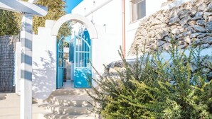 A white building with a stone wall, a blue door, and a red lamp post. - Villa Paola - Cosy private villa near the sea (Monacizzo-librari-truglione)