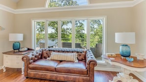 A spacious room with a brown leather sofa, a large window with a view of trees, and two side tables with lamps. - Yellowhammer Hill - Amenities galore! Near Cullman (Cullman)