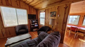 A cozy cabin interior with a sofa, a bookshelf, a desk, and a chair. - Superior Reflections Cabin 3 (Schroeder)