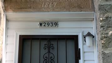 L’entrée d’un immeuble est ornée d’une arche en pierre, d’une enseigne indiquant « DEUTSCHER BAKKERIE 1867 » et d’une porte surmontée d’un portail en métal.