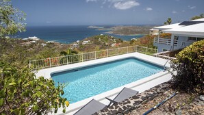 Piscina com vista para o oceano e colinas.