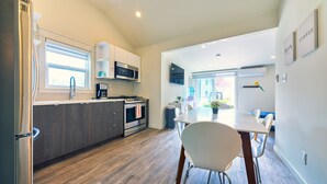 Eine moderne Küche mit Kühlschrank, Mikrowelle, Herd und Spüle. Ein Essbereich mit Tisch und Stühlen ist ebenfalls vorhanden.