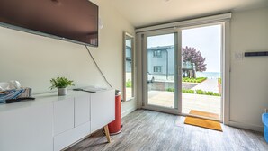 Ein modernes Zimmer mit einer Schiebetür zum Balkon, einem weißen Beistelltisch, einem roten Mülleimer und einem kleinen Topfpflanzen.