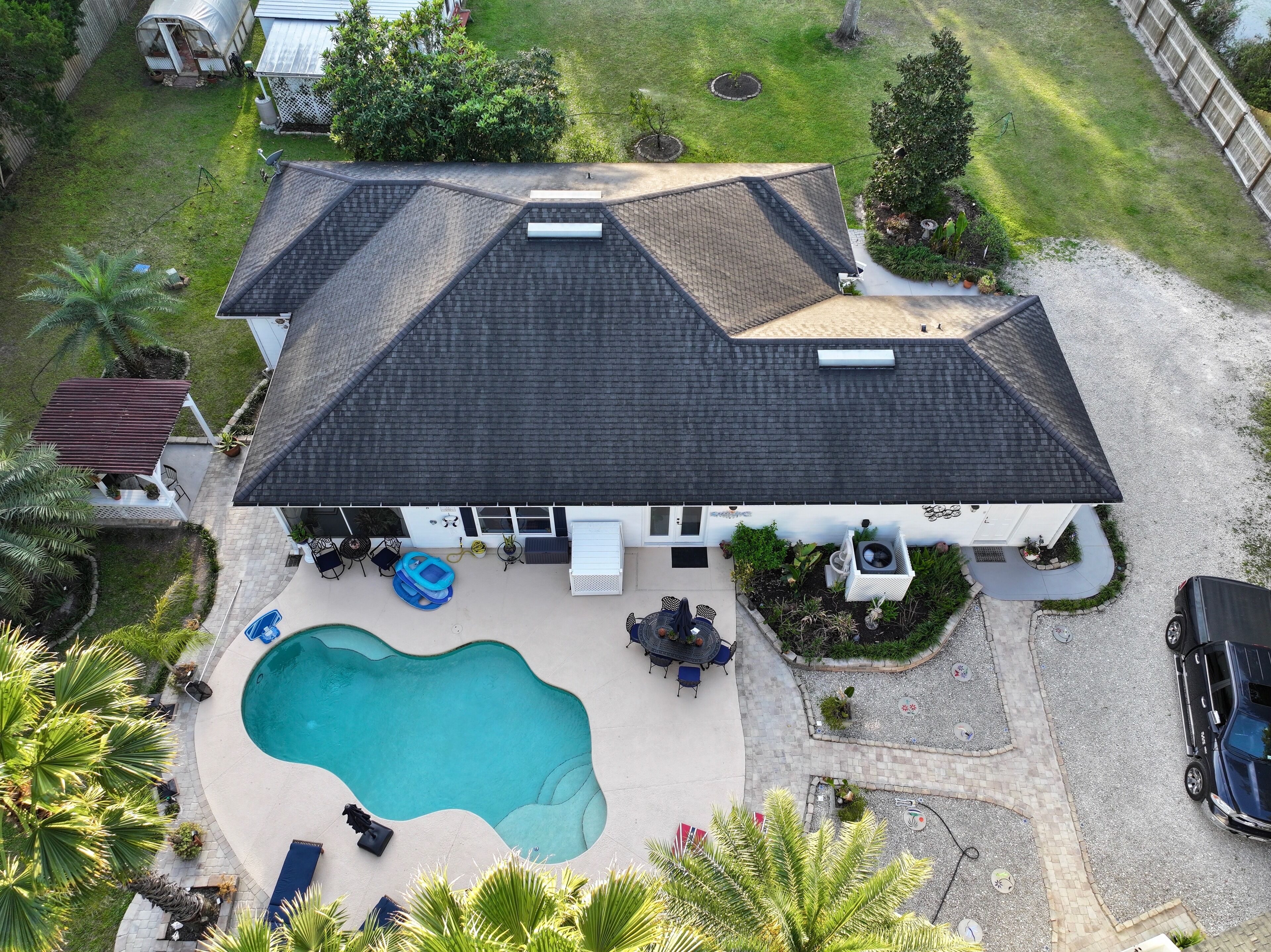 Ein Haus mit Swimmingpool, Terrassenmöbeln und einem eingezäunten Garten.