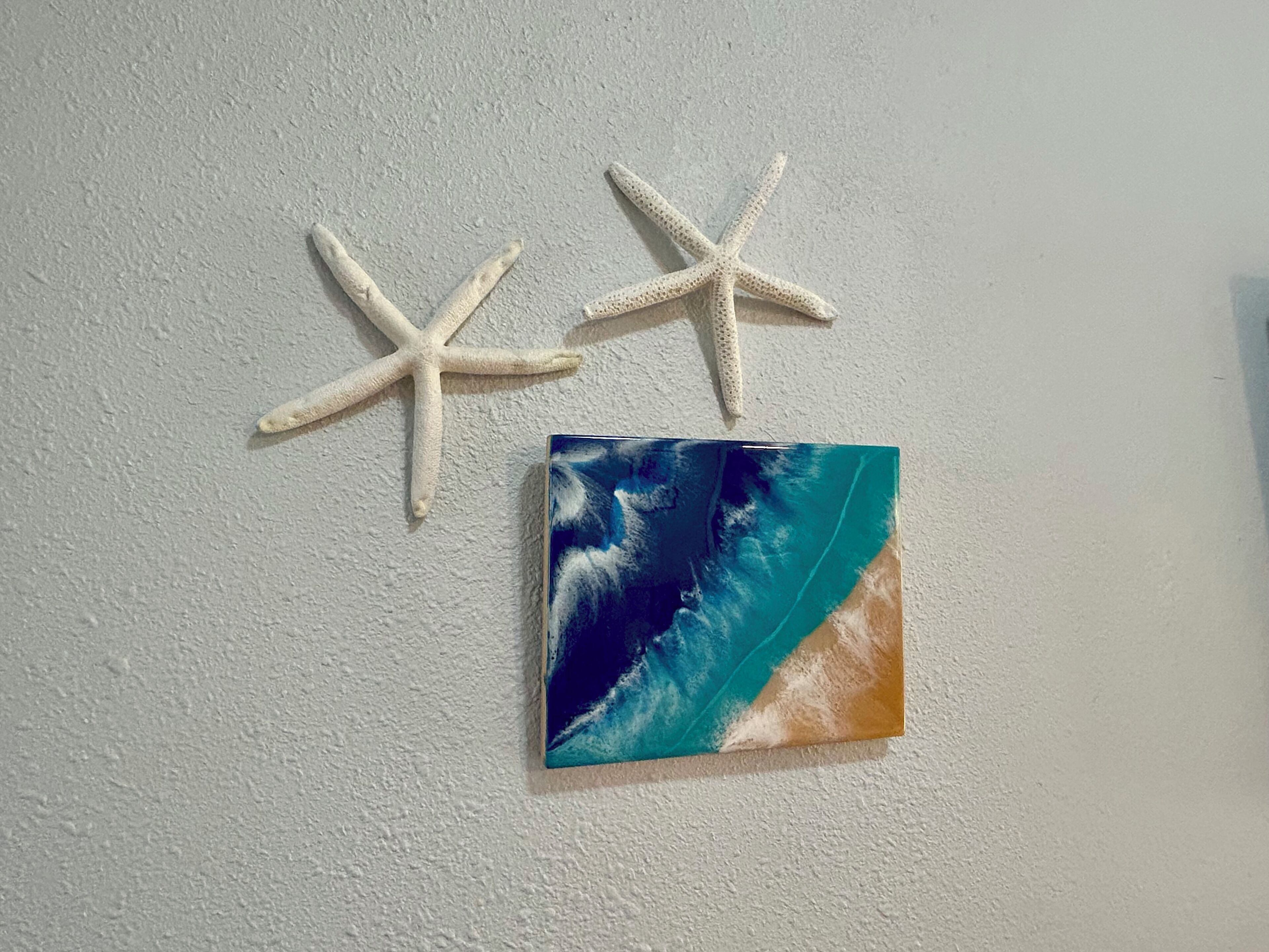 A wall with two starfish and a painting of a wave.