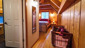 A wooden interior with a bed, a nightstand, and a wicker basket.