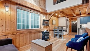 A wooden interior with a TV, a dining table, and a kitchen area.
