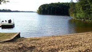 A sandy beach with a dock and a boat. - Northwoods waterfront Rhinelander Cabin getaway (Rhinelander)