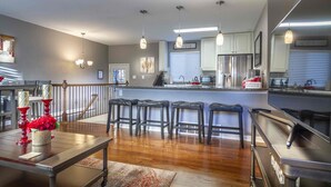 A modern kitchen with a central island, bar stools, and a dining table with red candle holders.
