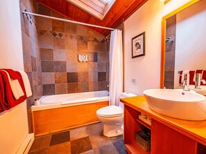 Een badkamer met een bad, toilet en een ruime wastafel.