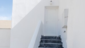A set of black marble stairs leading to a white door, surrounded by white walls and a clear sky. - Aislin House: Where Beachfront Bliss Meets Santorini Charm! (Santorini)