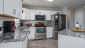 A modern kitchen with white cabinets, stainless steel appliances, and a marble countertop.