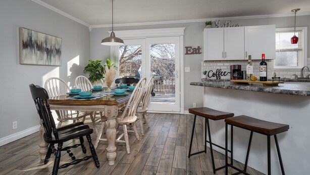 A modern kitchen with a dining area, featuring a wooden table, chairs, and a bar area.