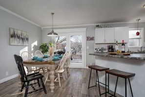Una cocina moderna con comedor, que incluye una mesa de madera, sillas y una barra.