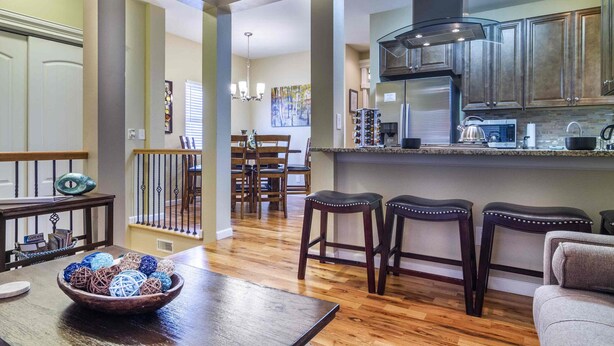 A spacious kitchen with wooden cabinets, a stainless steel refrigerator, and a dining area with a wooden table and chairs. - Best Views Street (Colorado Springs)
