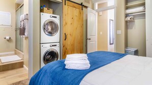 A hotel room with a bed, a washing machine, a drying rack, and a closet. - Best Views Street (Colorado Springs)