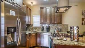 A modern kitchen with stainless steel appliances, wooden cabinets, a granite countertop, and a gas stove. - Best Views Street (Colorado Springs)