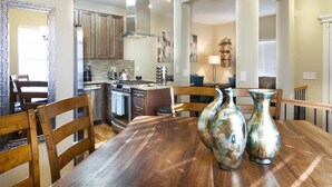 A dining area with a wooden table, two vases, and a kitchen in the background. - Best Views Street (Colorado Springs)