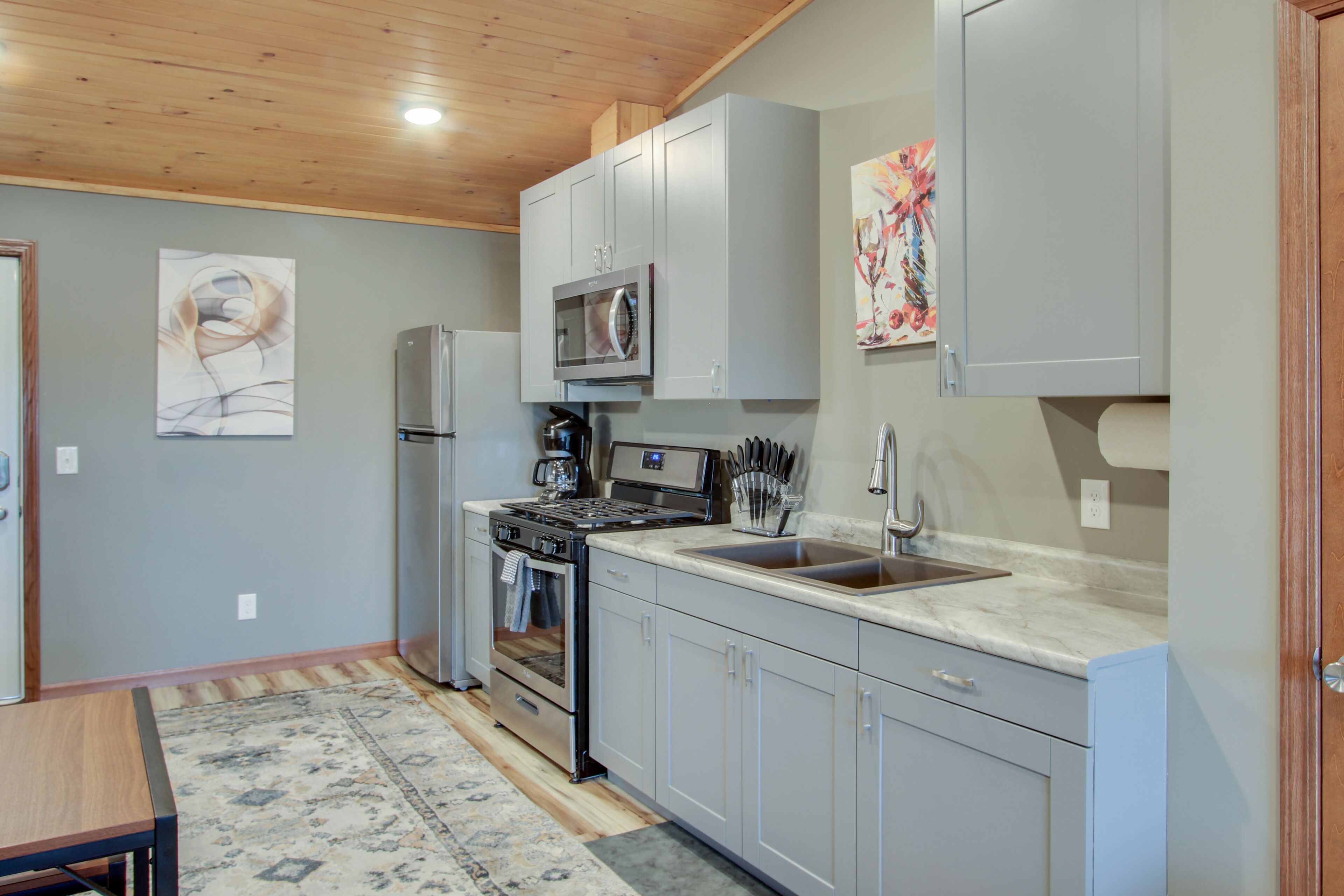 A kitchen with grey cabinets, a microwave, a stove, and a sink.