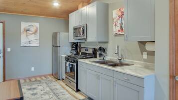 A kitchen with grey cabinets, a microwave, a stove, and a sink.