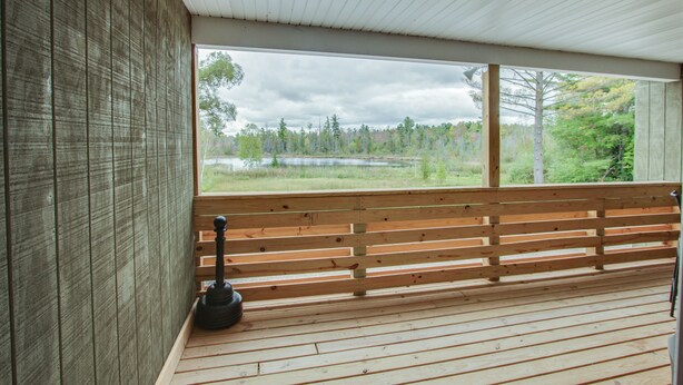 A wooden deck with a bench and a view of a lake and forest. - The 4th Overlook Seeps 4, In-between Crystal Mountain and Traverse City! WI-FI  (Interlochen)