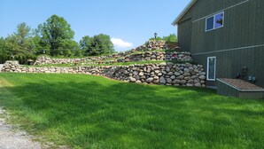 A building with a stone retaining wall and a grassy lawn. - The 4th Overlook Seeps 4, In-between Crystal Mountain and Traverse City! WI-FI  (Interlochen)