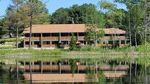 A two-story building with a flat roof, surrounded by trees and a body of water. - The 4th Overlook Seeps 4, In-between Crystal Mountain and Traverse City! WI-FI  (Interlochen)