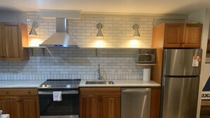 A modern kitchen with stainless steel appliances, wooden cabinets, and a tiled backsplash. - Sugarloaf Ski-In/Ski-Out Condo – Golf, Bike & Hike (Carrabassett valley)