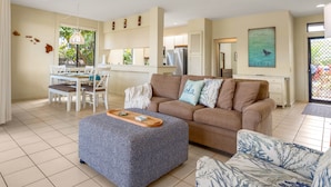 A living room with a sofa, ottoman, and a dining area with chairs and a table.