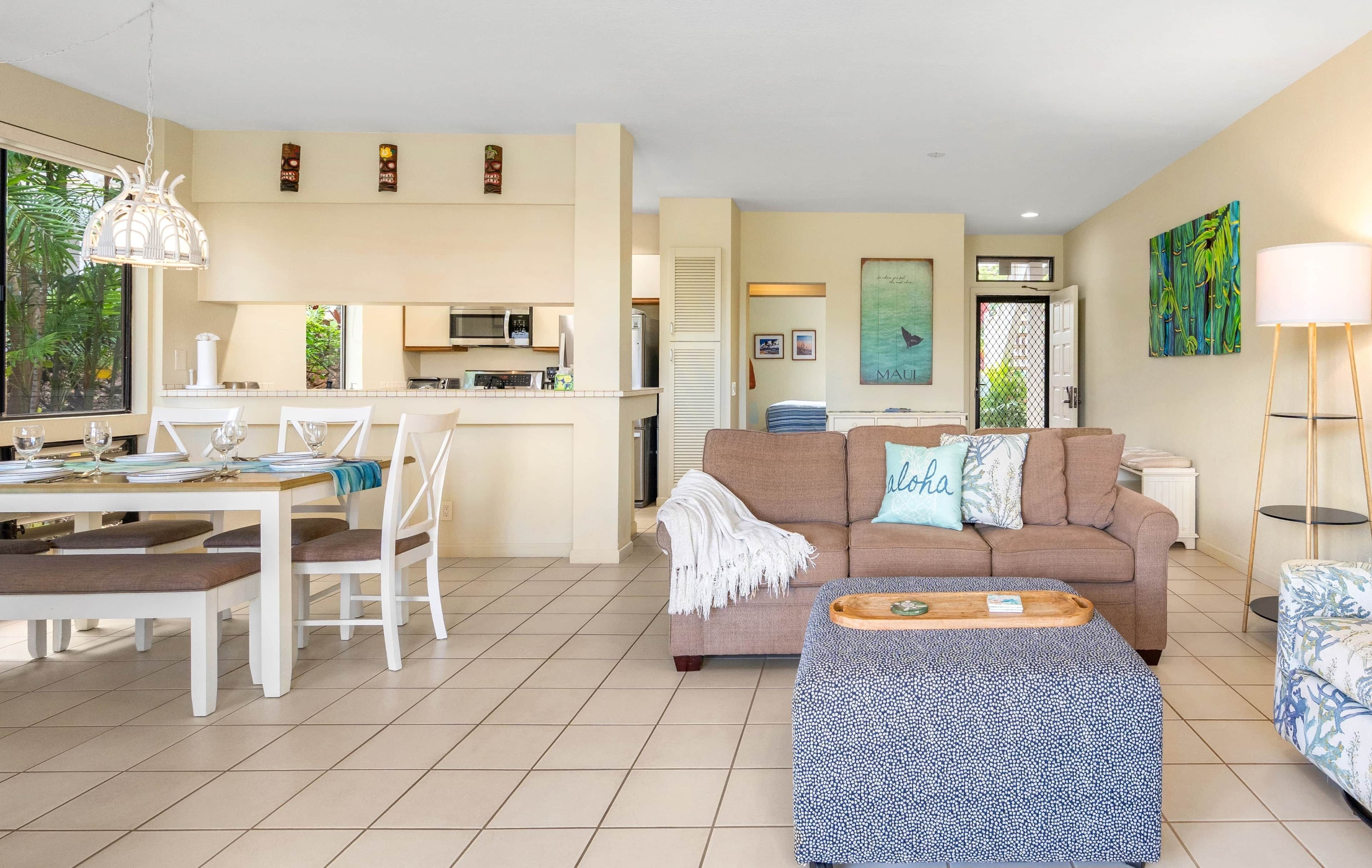 A modern living room with a sofa, dining table, and kitchen area.
