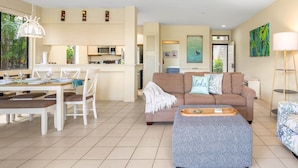 A modern living room with a sofa, dining table, and kitchen area.
