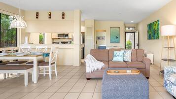 A modern living room with a sofa, dining table, and kitchen area.