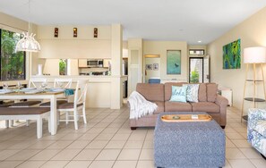Una sala de estar moderna con sofá, mesa de comedor y zona de cocina.