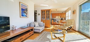 Un salon moderne avec un canapé, une table basse en verre, un téléviseur et un meuble de rangement en bois.