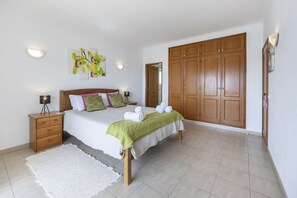 Ein Schlafzimmer mit einem Bett, Nachttischen, einem Kleiderschrank und einer Tür.