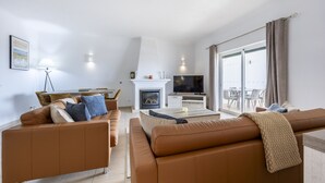 Ein modernes Wohnzimmer mit Kamin, Fernseher und Essbereich.