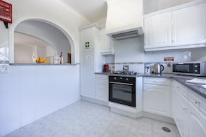 A modern kitchen with white cabinetry, a gas stove, an oven, and a microwave. - CoolHouses Algarve Luz | Blue Ocean View T2 (Luz)