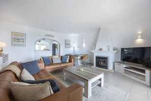 Ein modernes Wohnzimmer mit Ledersofa, Couchtisch aus Holz, Kamin und Flachbildfernseher.