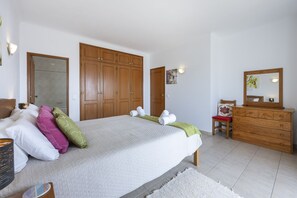 A bedroom with a bed, a dresser, a chair, and a mirror.