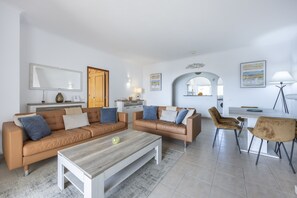 Ein modernes Wohnzimmer mit zwei Sofas, einem Couchtisch und einem Essbereich mit Stühlen.