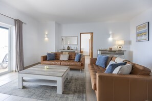A modern living room with a brown leather sofa, a white coffee table, and a grey rug.