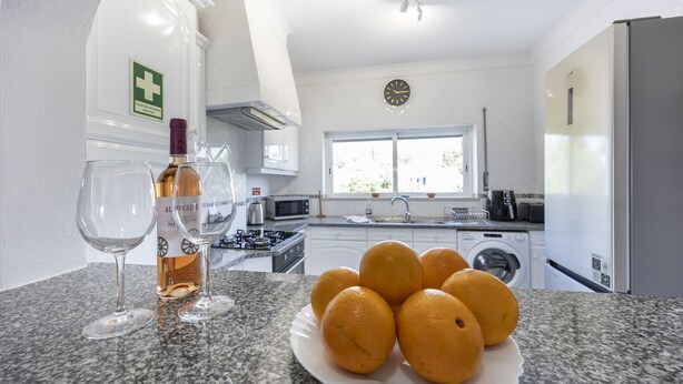 Eine Küche mit einer Arbeitsplatte aus Granit, einer Weinflasche, zwei Gläsern und einem Teller Orangen.