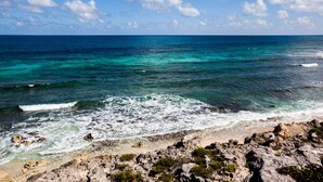 A coastal landscape with clear turquoise waters, rocky shoreline, and a clear sky. - Casa Nido del Gallo Solar Ocean Front Deluxe Home 3 bedrooms, 5 bathrooms (Isla Mujeres)