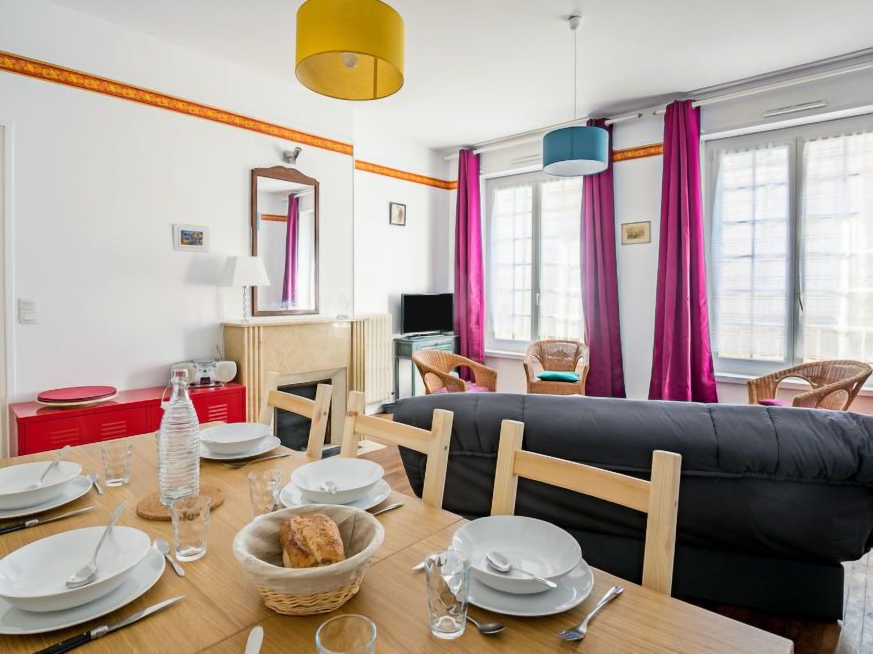 Habitació d'hotel moderna amb zona de menjador, sofà i televisió.