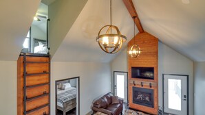 Een slaapkamer in loft-stijl met een hoogslaper, een leren bank, een open haard en een eethoek.
